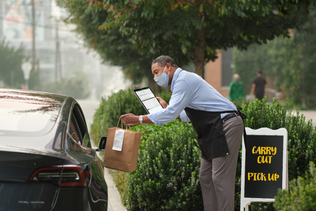 Male restaurant worker providing curbside pick-up for customers.