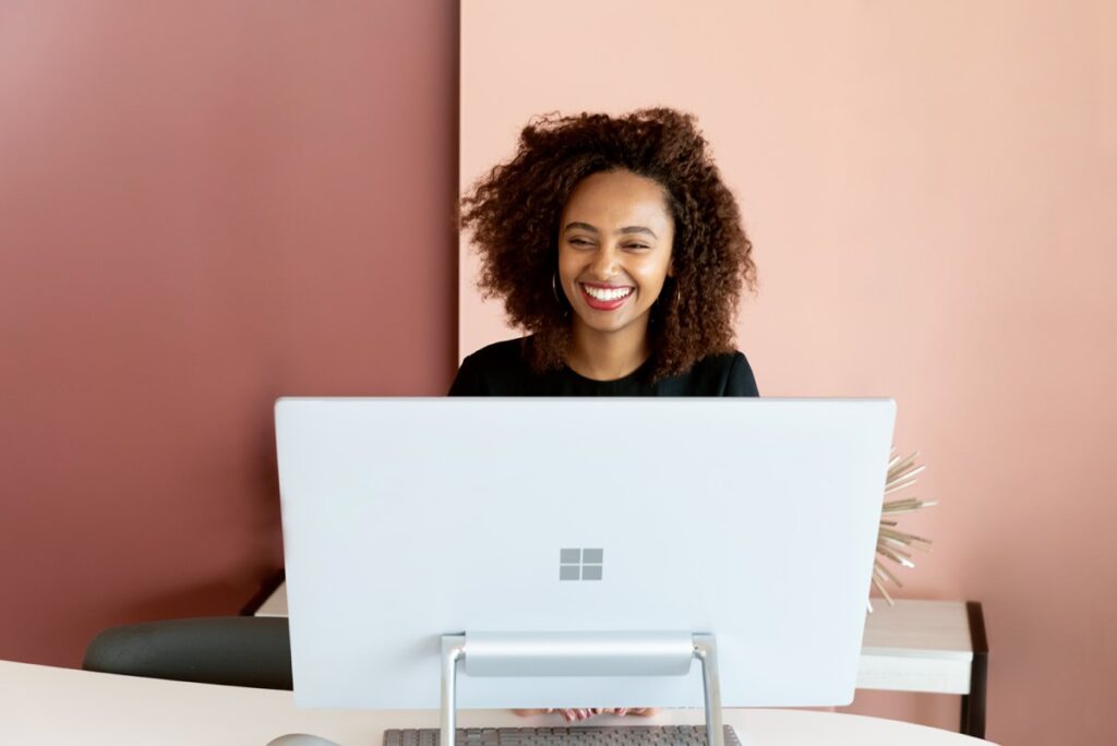 Smiling woman sitting behind a Microsoft-branded computer.