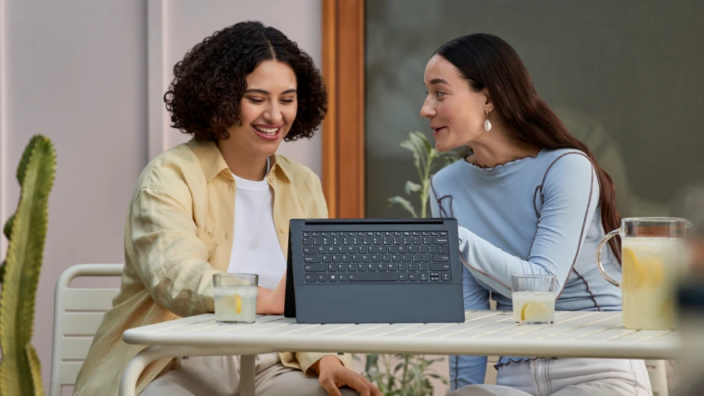 Two hybrid employees sharing a device and collaborating.