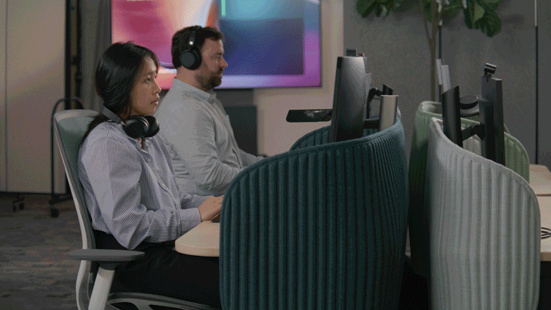两个人坐在办公桌前的短视频，然后放大到 Microsoft Teams 用户界面，其中打开了智能会议回顾，显示会议中的不同发言者都归属于会议记录。 