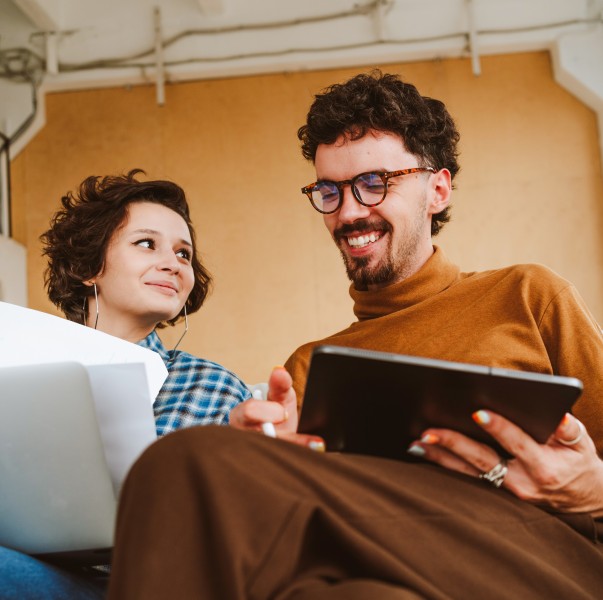 A smiling illustrator sitting with coworker at an office.