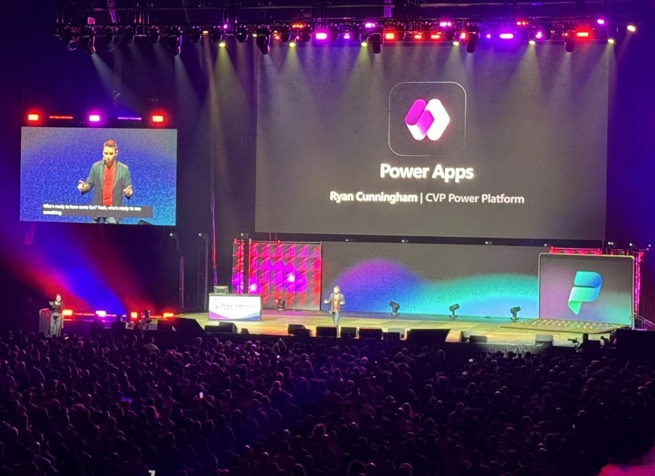 Keynote presentation at a large conference featuring Power Apps and Power Platform branding displayed on stage screens before a large audience.
