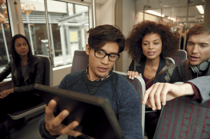 Four people looking at a tablet together in an office.
