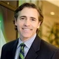 a man wearing a suit and tie smiling at the camera