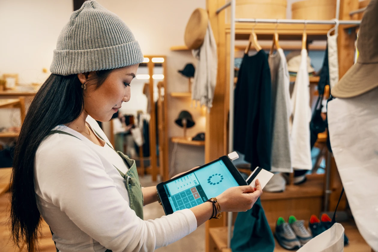 Shop clerk in a clothing boutique taking a credit card payment on a digital tablet