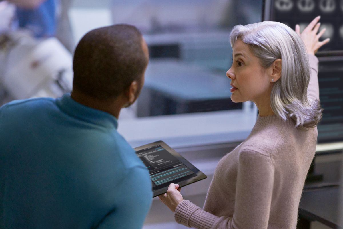A woman holding a tablet with a man looking at it