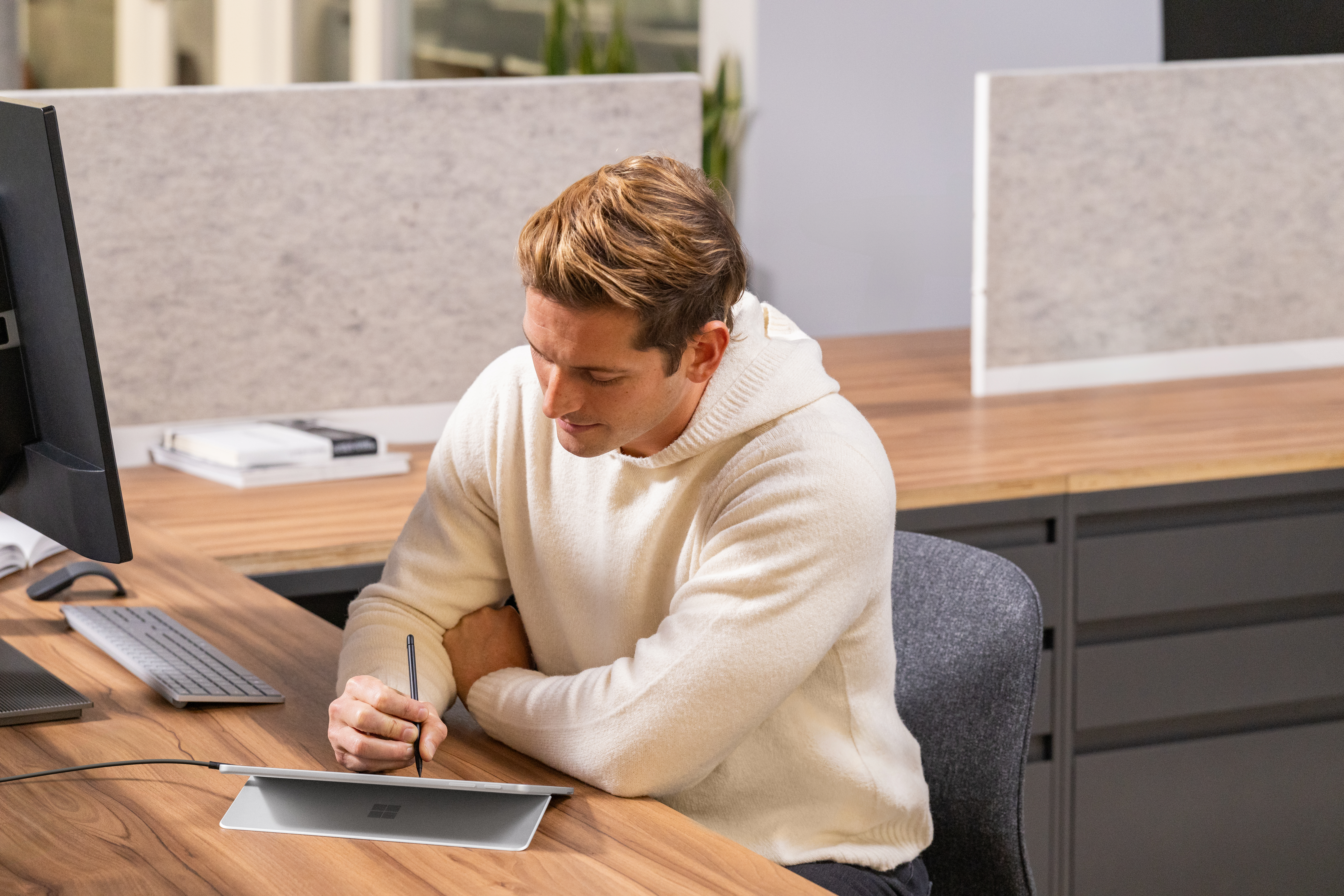 A man sitting at a desk with a tablet and a computer