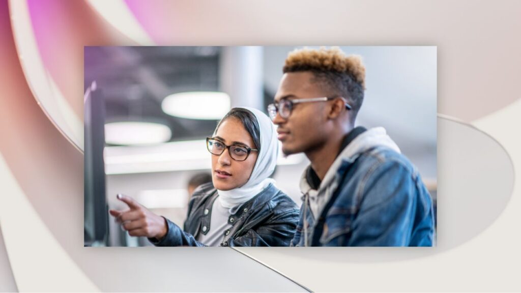 Two makers looking at a computer screen and collaborating in an office setting.