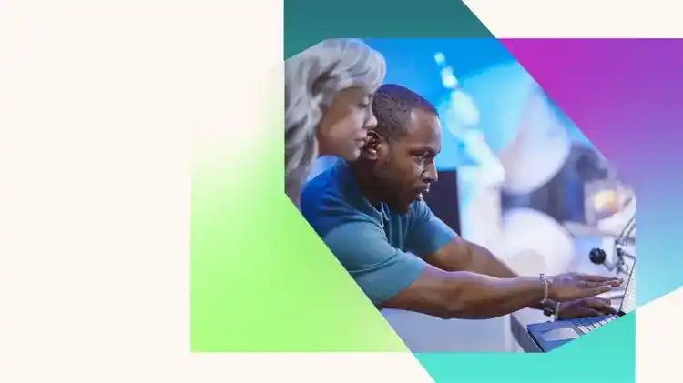 Two colleagues focus on equipment in a blue-lit workspace, with one person reaching forward to adjust a control panel while the other leans in close to watch, all framed by overlapping green, teal, purple, and blue geometric shapes on a light background
