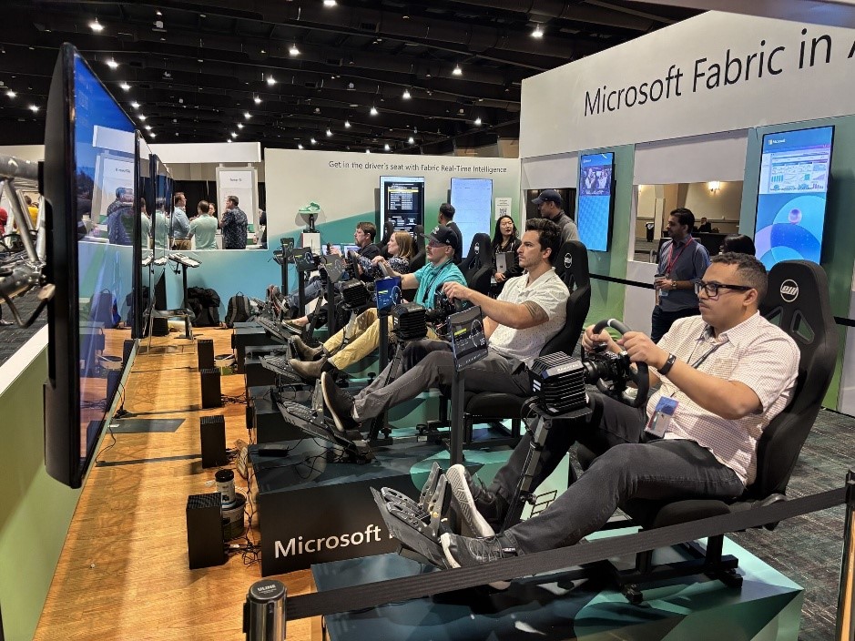 A group of people looking at screens while sitting in chairs that include pedals and steering wheels.