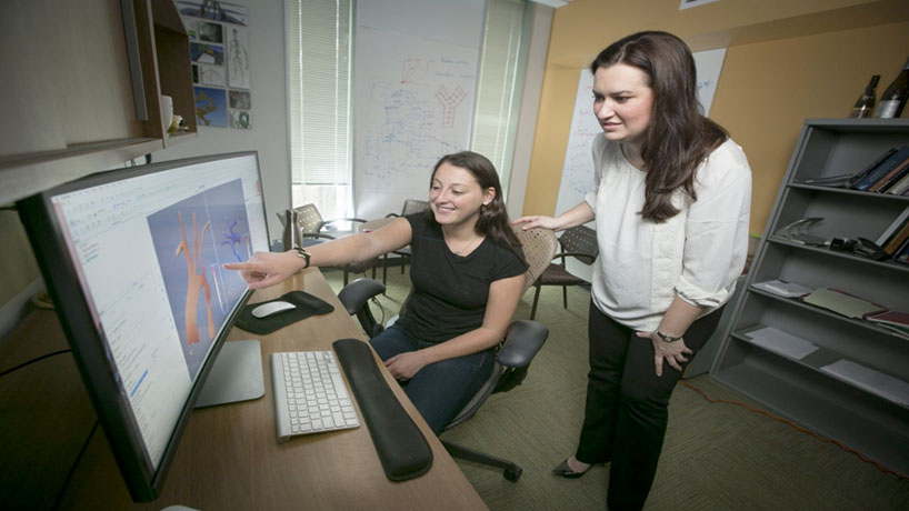 Dr. Amanda Randles from Duke University working with a member of her team at a computer.