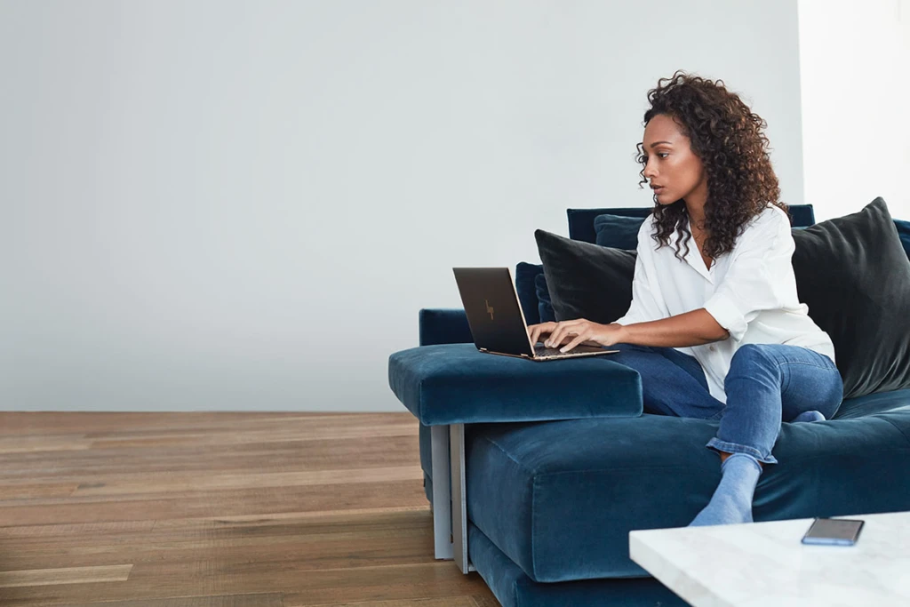 A person sitting in a blue chair using a laptop.