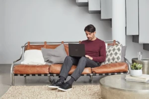Man sitting on couch working on laptop.