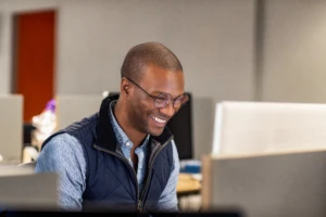 Real people, real offices. Black male developer smiling while at work in an Enterprise office workspace. Focused work. Code, develop, black developer, engineer, Visual Studio, Azure.