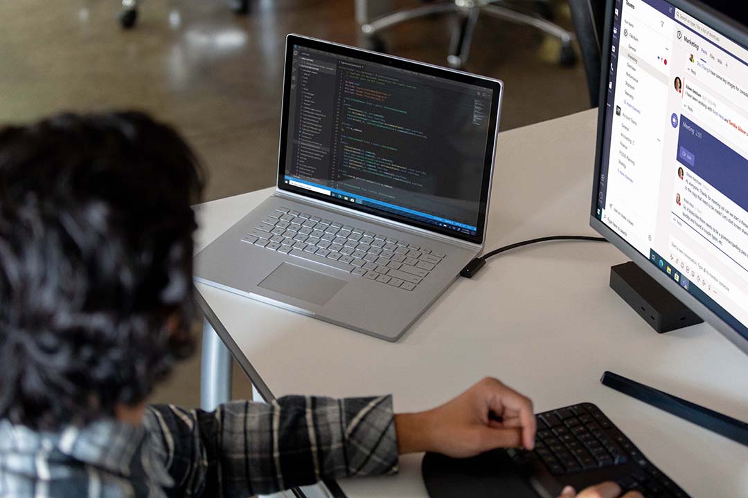 a person sitting at a desk in front of a laptop computer