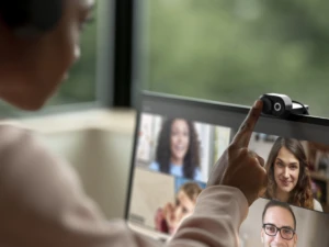 Adult female inside wearing Microsoft Modern Wireless Headset and turning on Microsoft Modern Webcam while on a Microsoft Teams call