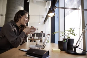 Female small business professional at desk working on an HP Elite Book using Microsoft Teams. Open office.