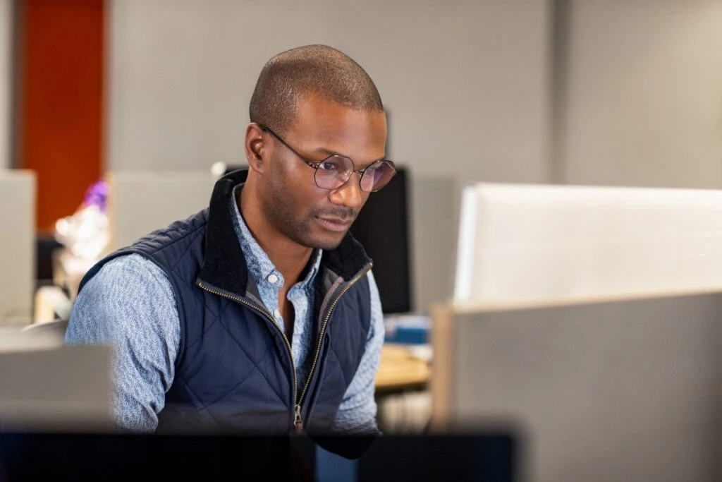 Real people, real offices. Black male developer at work in an Enterprise office workspace. Focused work. Code, develop, black developer, engineer, Visual Studio, Azure.