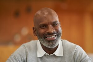 Close-up portrait of a man, smiling, looking past the camera.