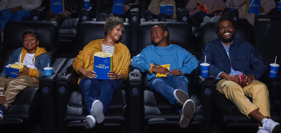 A group of people sitting next to each other in a movie theater.