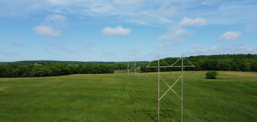 A field with a power pole standing in the center, surrounded by open space and natural scenery.