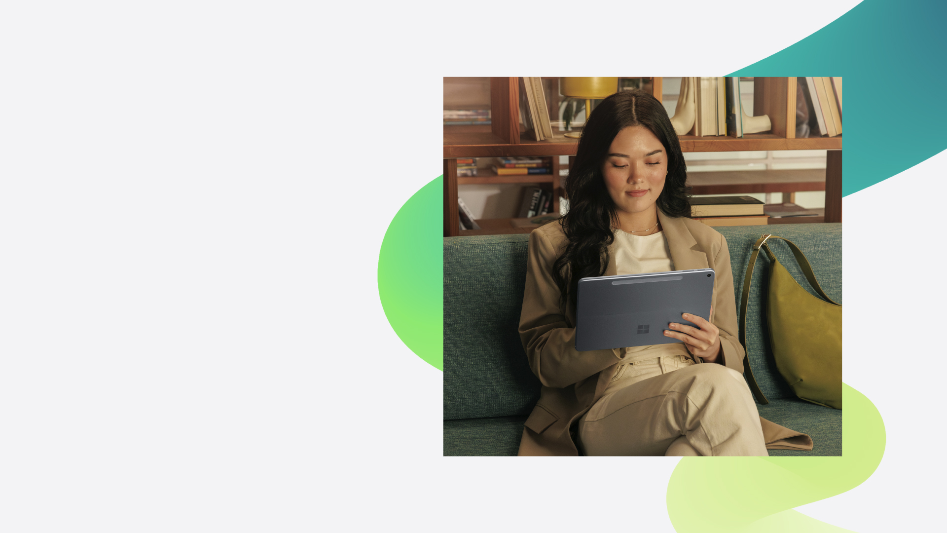 A business manager working on a surface device in a common area at an office.