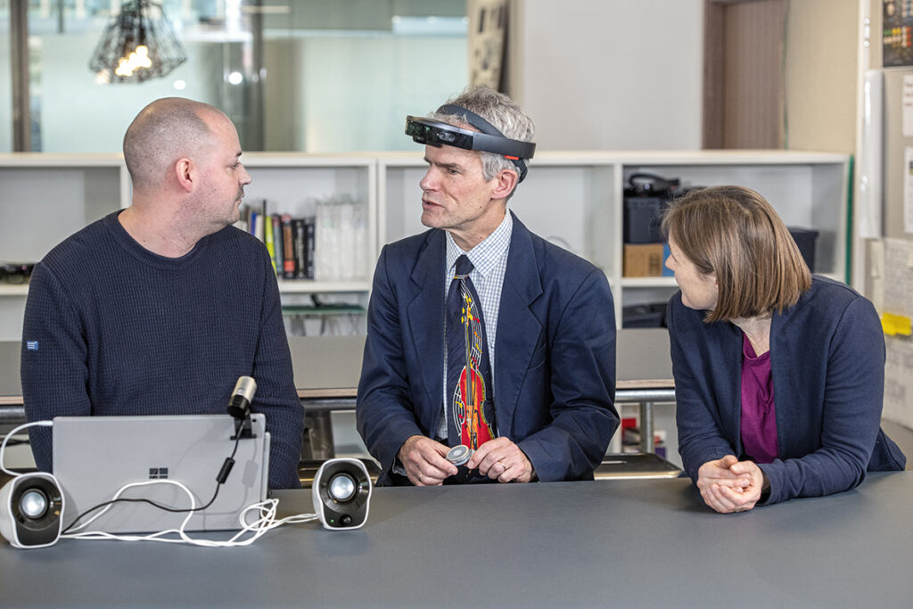 Peter Bosher, middle, an audio engineer who is blind who worked with the Project Tokyo team early in the design process, checks out the latest iteration of the system at Microsoft’s research lab in Cambridge, UK, with researchers Martin Grayson, left, and Cecily Morrison, right. Photo by Jonathan Banks.