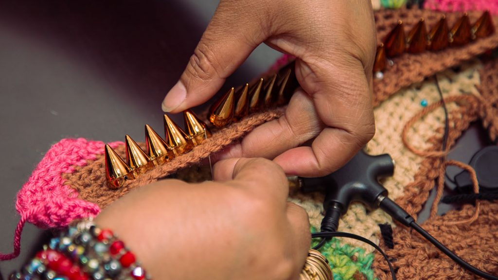 Project Brookdale: photo of a woman's hands sewing accessories onto a woven garment