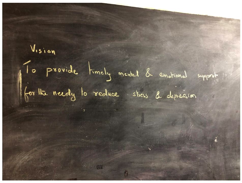 Text on chalkboard: Vision, to provide timely mental and emotional support for the needy to reduce stress and depression.