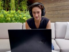 Ester Baiget sitting at a table with a laptop and smiling at the camera