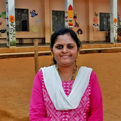 Ms. Parimala standing in front of a school