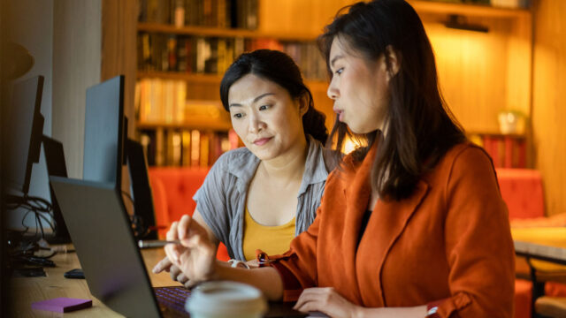 AI4Good - Expand Opportunity | photo of two women looking at a laptop screen conversing