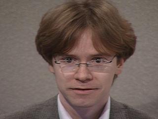 a person wearing a suit and tie smiling at the camera