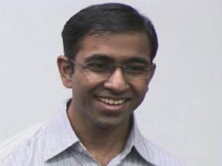 a man wearing glasses and smiling at the camera