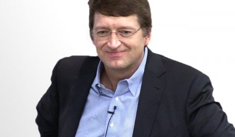 a man wearing a suit and tie smiling at the camera