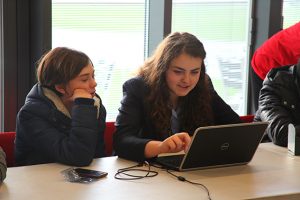 Danielle Dax et al. sitting at a table using a laptop computer