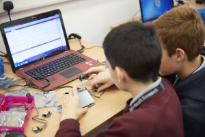 a group of people sitting at a table using a laptop computer