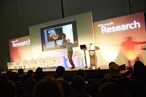 a group of people in front of a crowd of people watching a screen