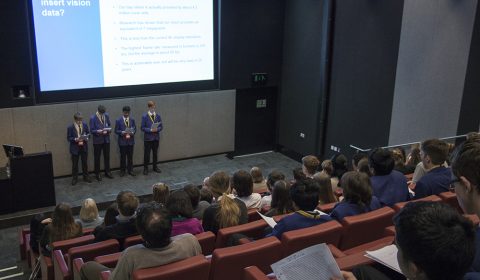 a group of people sitting in front of a large screen