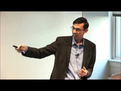 a man in a suit standing in front of a flat screen tv
