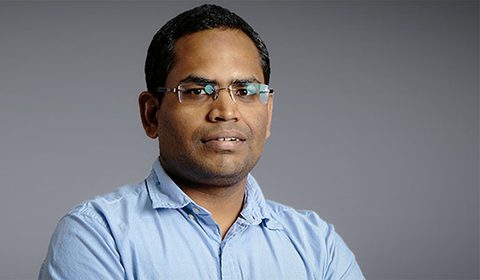 a man wearing glasses and smiling at the camera