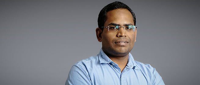 a man wearing glasses and smiling at the camera