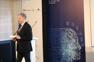 Eric Horvitz in a suit standing in front of a store