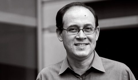 a man wearing glasses and smiling at the camera