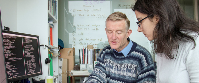 Simon Peyton Jones writing with a fellow researcher at a desk