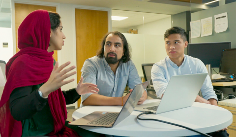 a group of people looking at a laptop