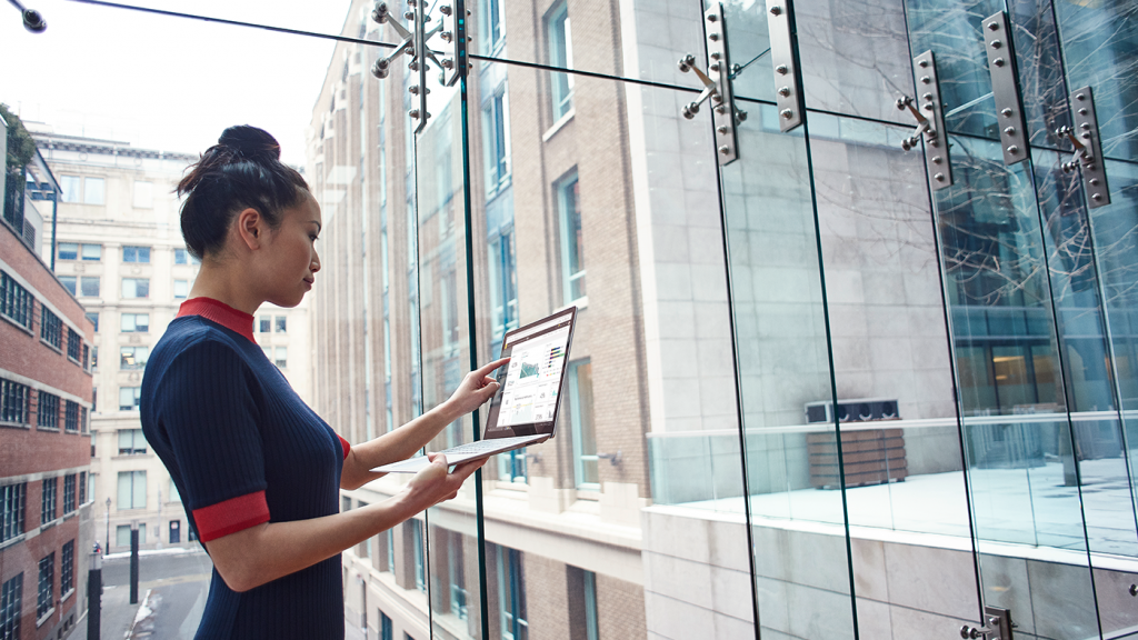 woman in the city holding and looking at an opened laptop