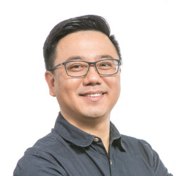 a man wearing glasses and smiling at the camera