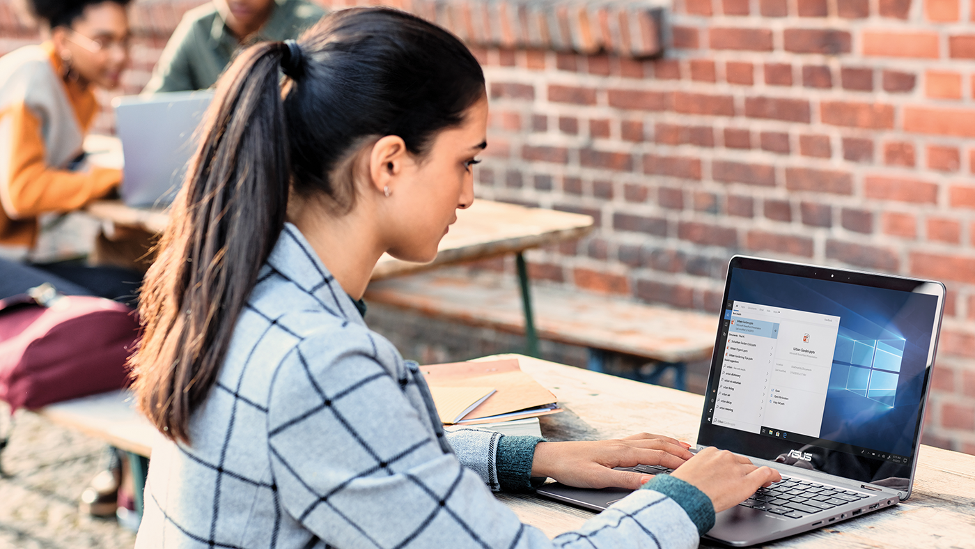 a woman using a laptop computer sitting on top of a building