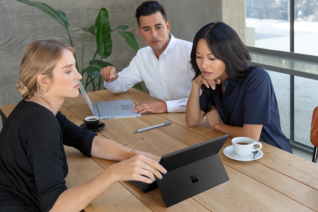 Three people sit around a table, sharing data